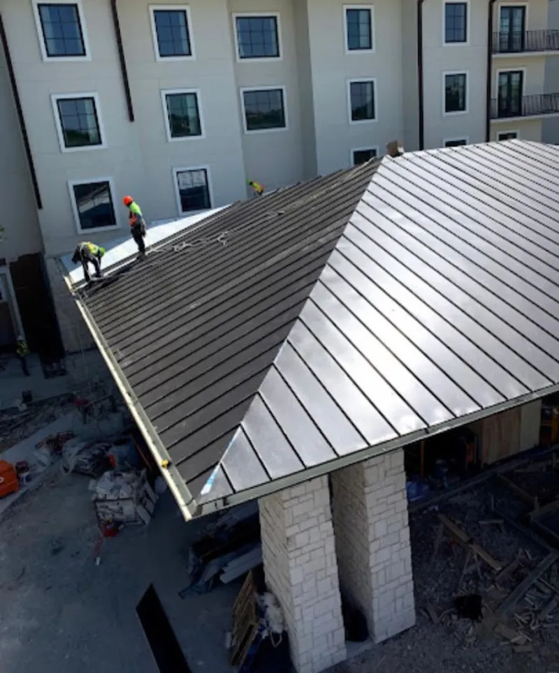 Crew installing standing seam metal roof panels on a commercial project in Taylorville